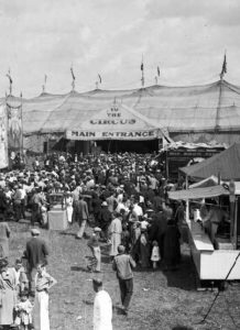 Entrée d'un cirque occupée par une grande foule.