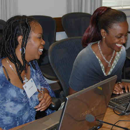 Deux dames travaillent à l'ordinateur en souriant.