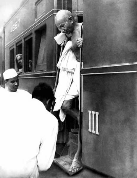 Gandhi debout sur l'escalier d'un train.