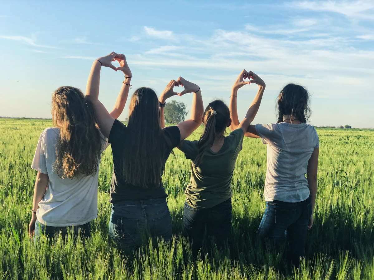 Quatre adolescentes font une forme de cœur avec leurs mains.