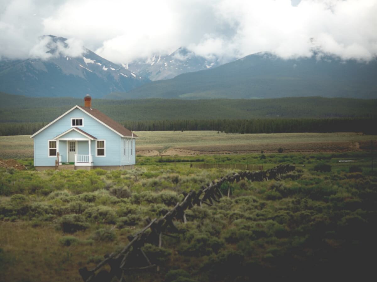 Une petite maison devant une chaîne de montagnes