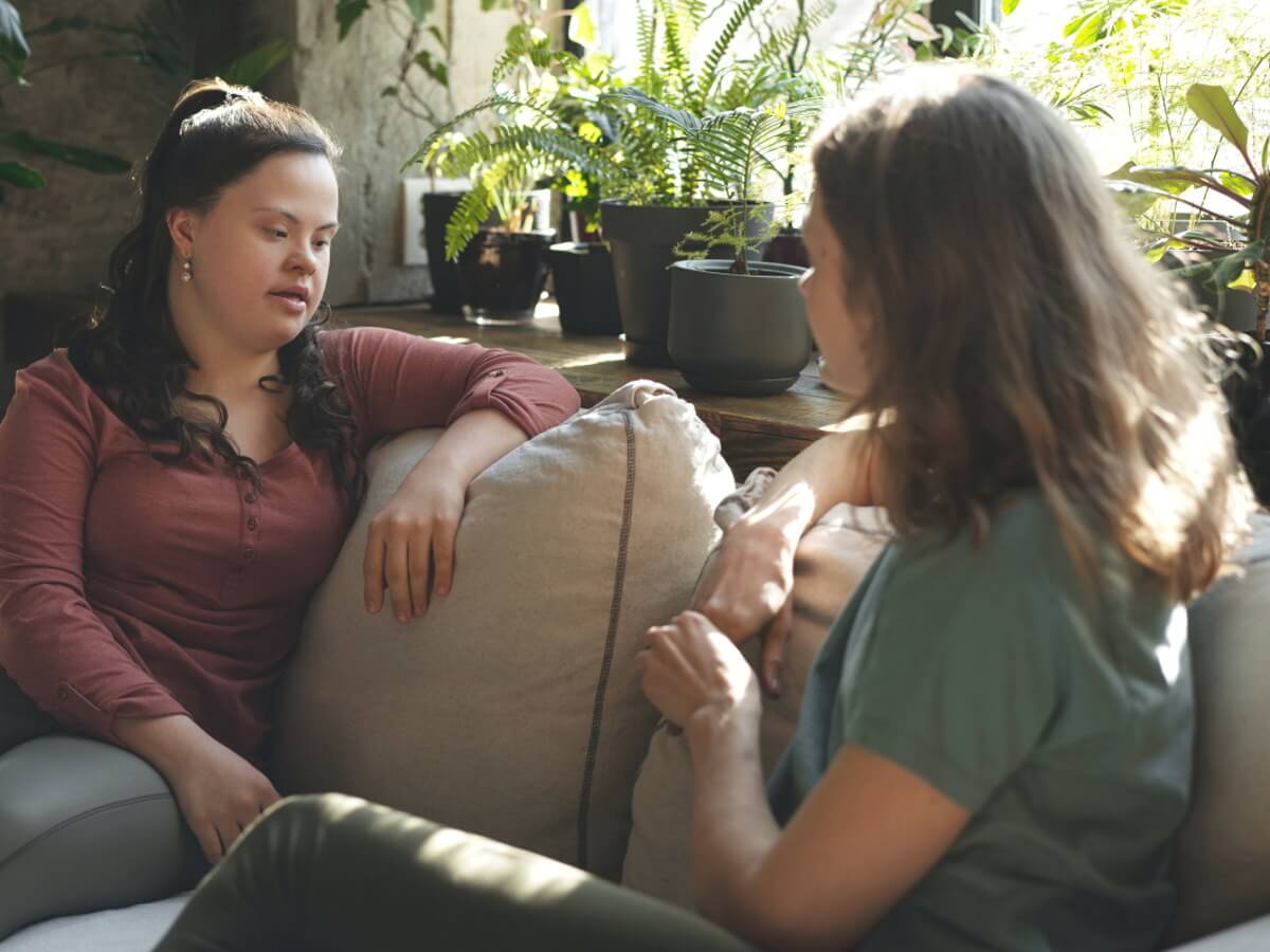 Deux dames échangent assises sur un sofa.