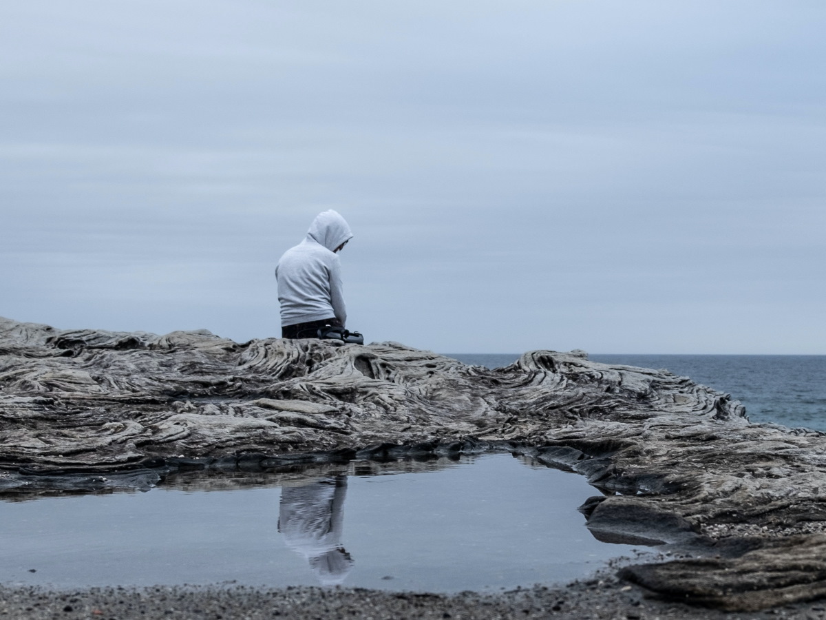 Une personne triste seule sur une plage.