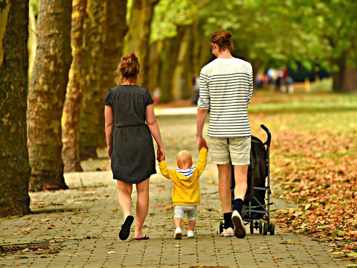 Un homme et une femme tiennent la main d’un jeune enfant.