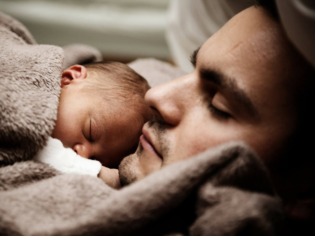 Un homme est allongé avec un nouveau-né dans les bras.