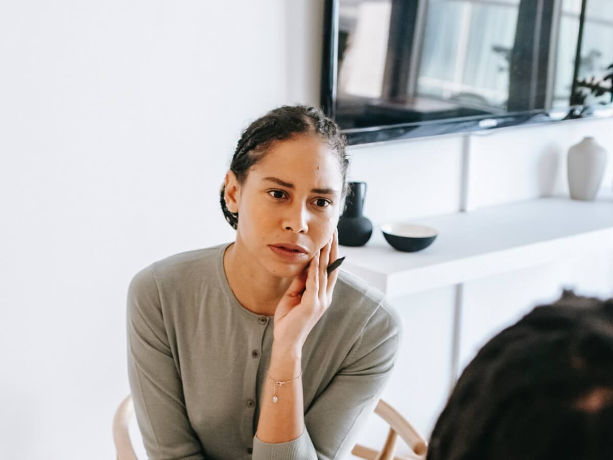 Une femme assise à une table écoute attentivement une autre personne.