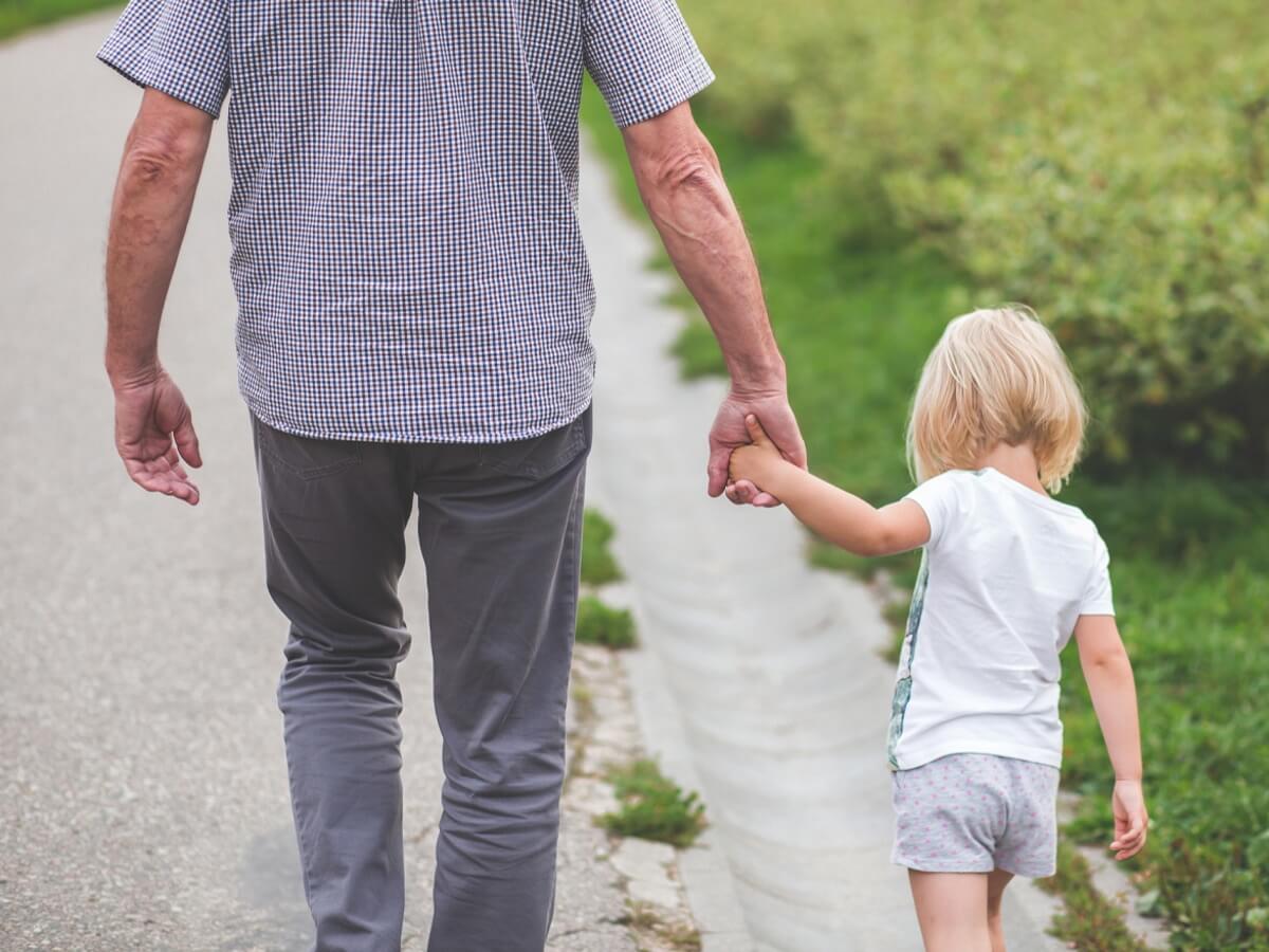 Un homme tient par la main un enfant d’environ 4 ans.