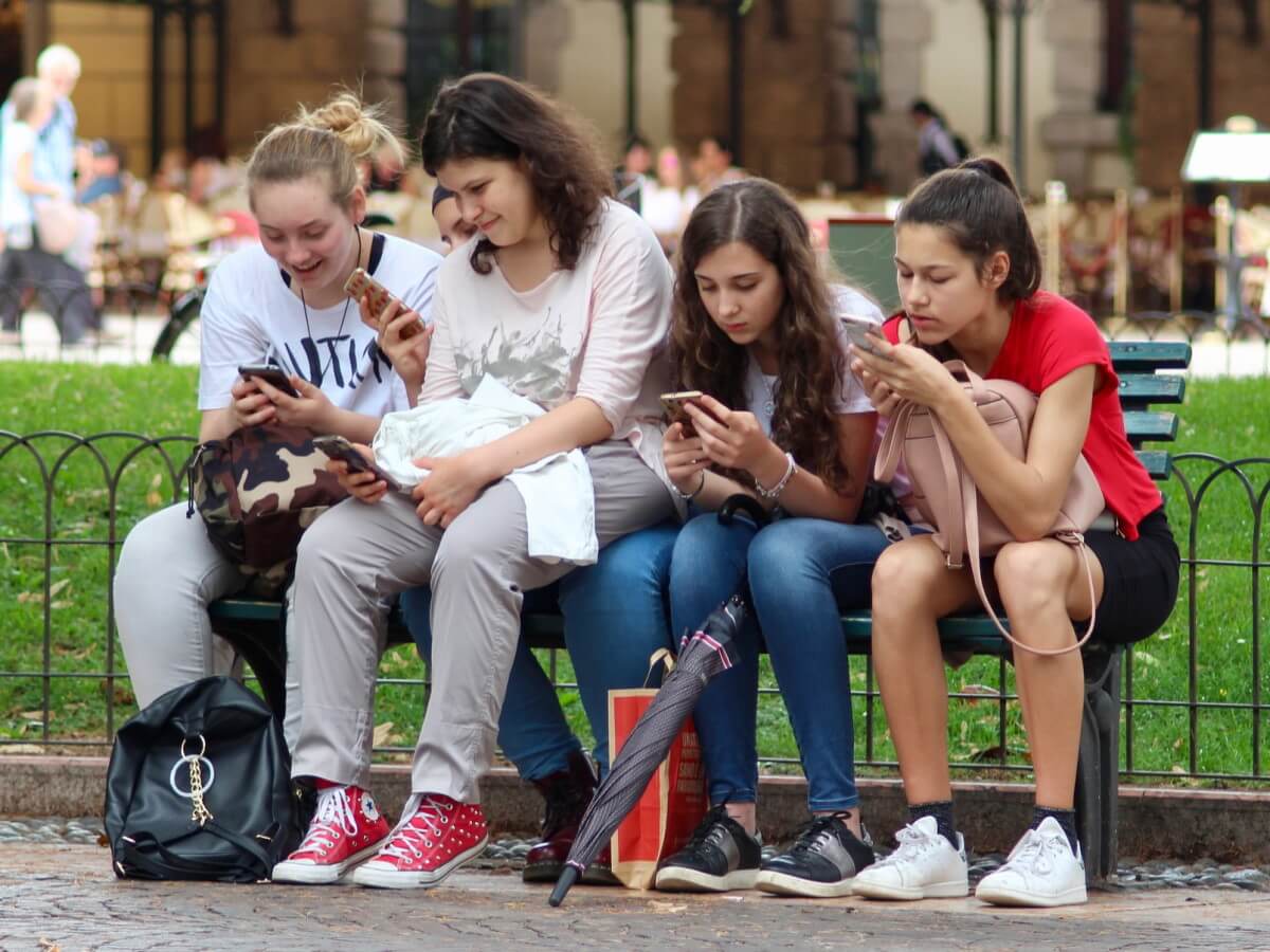 Quatre adolescentes tapent sur leur smart phone.