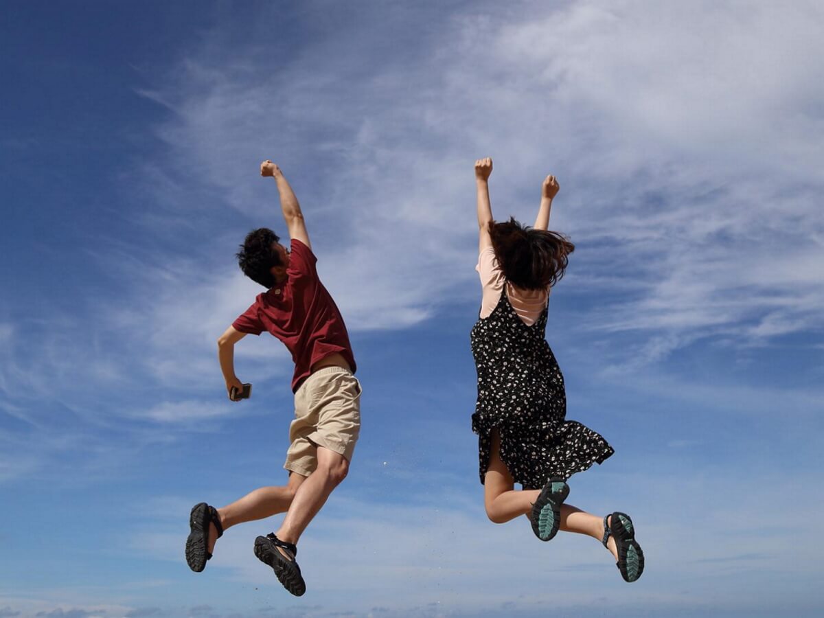 Deux jeunes gens sautent en l'air pour exprimer leur joie.