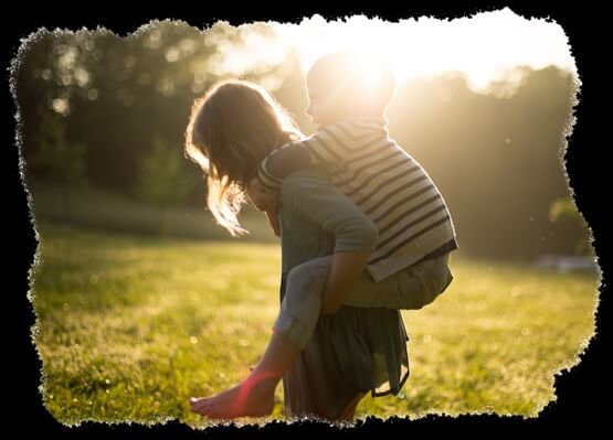 Une jeune fille porte un gamin sur son dos.