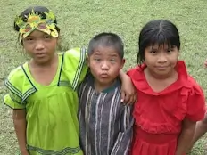 Trois enfants de 4 à 8 ans regardent la caméra.