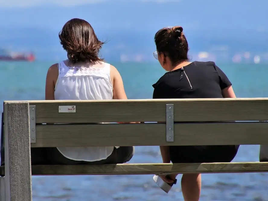 Deux femmes assises sur un banc de parc vues de dos