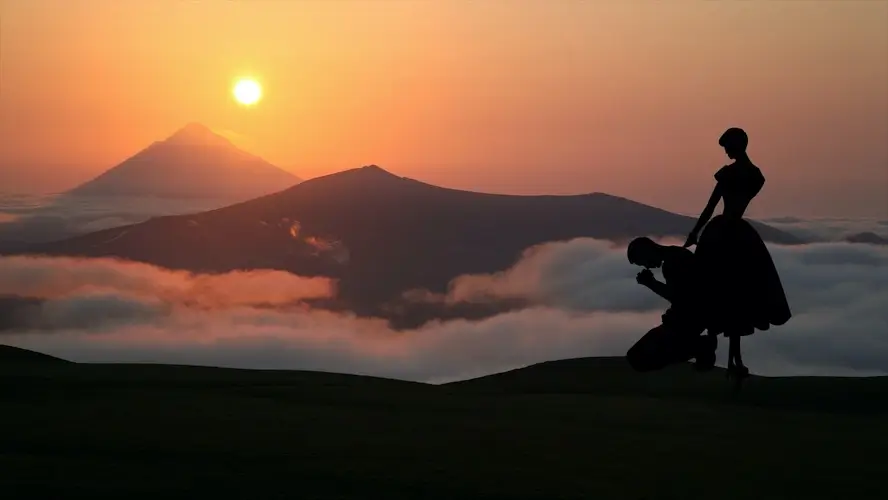 Une dame console un homme souffrant devant un coucher de soleil.