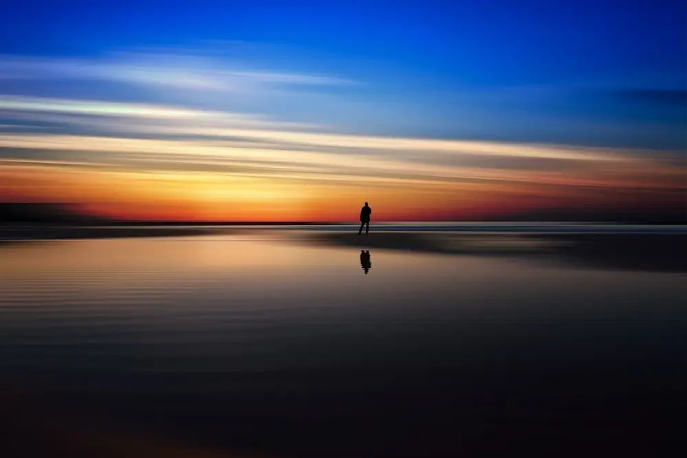 Un homme seul sur la plage devant un lever de soleil